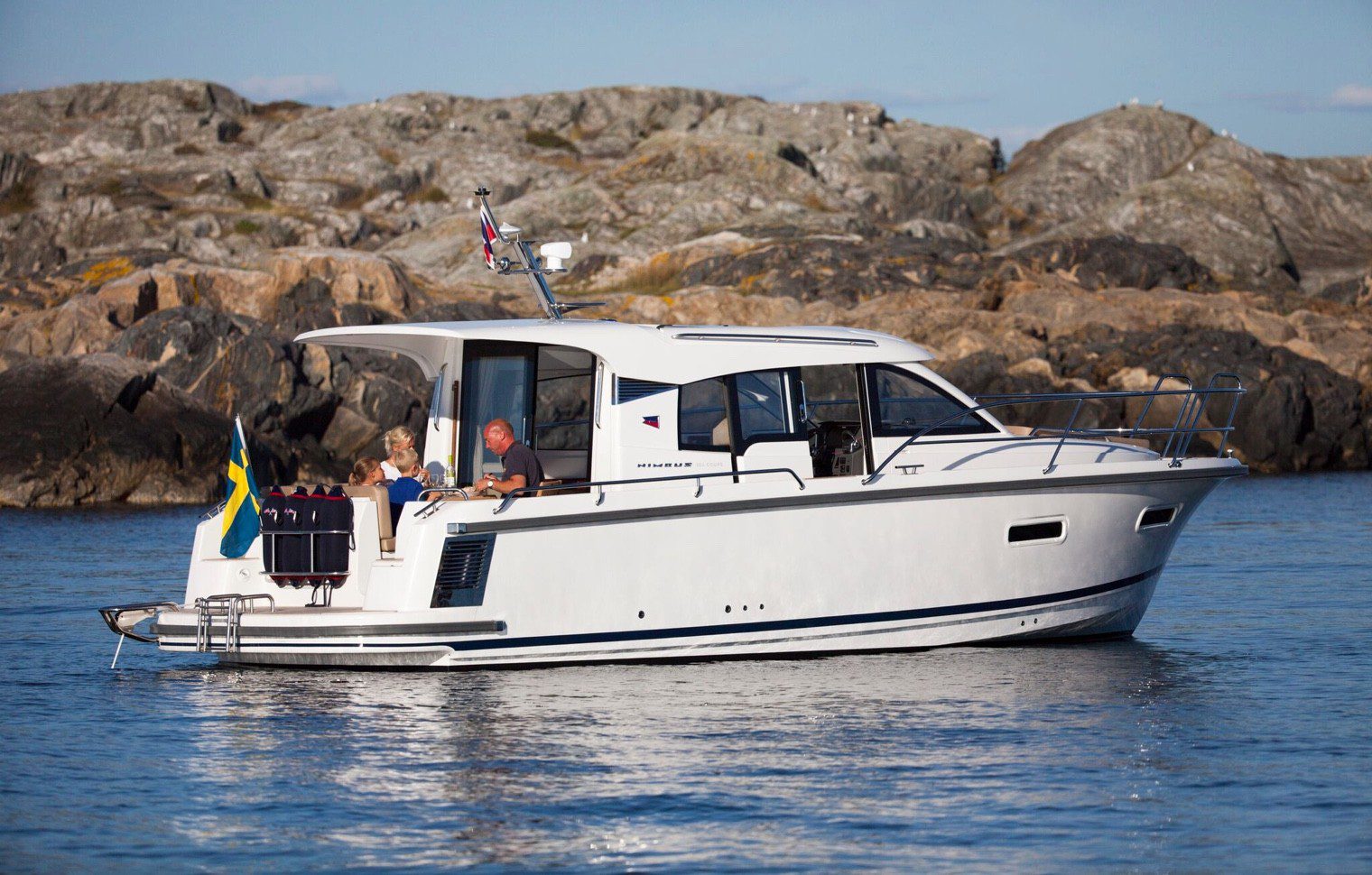 Boat from behind with people enjoying the day by a cliff