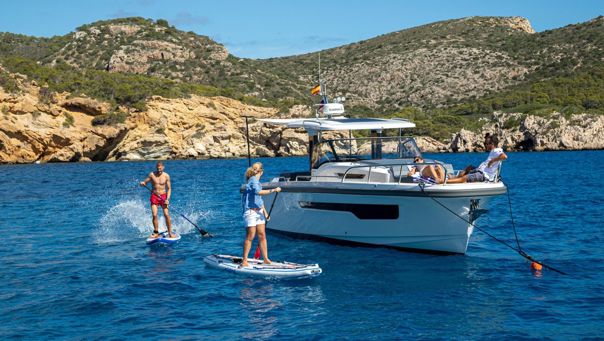 People paddel boarding next to a boat on the ocean