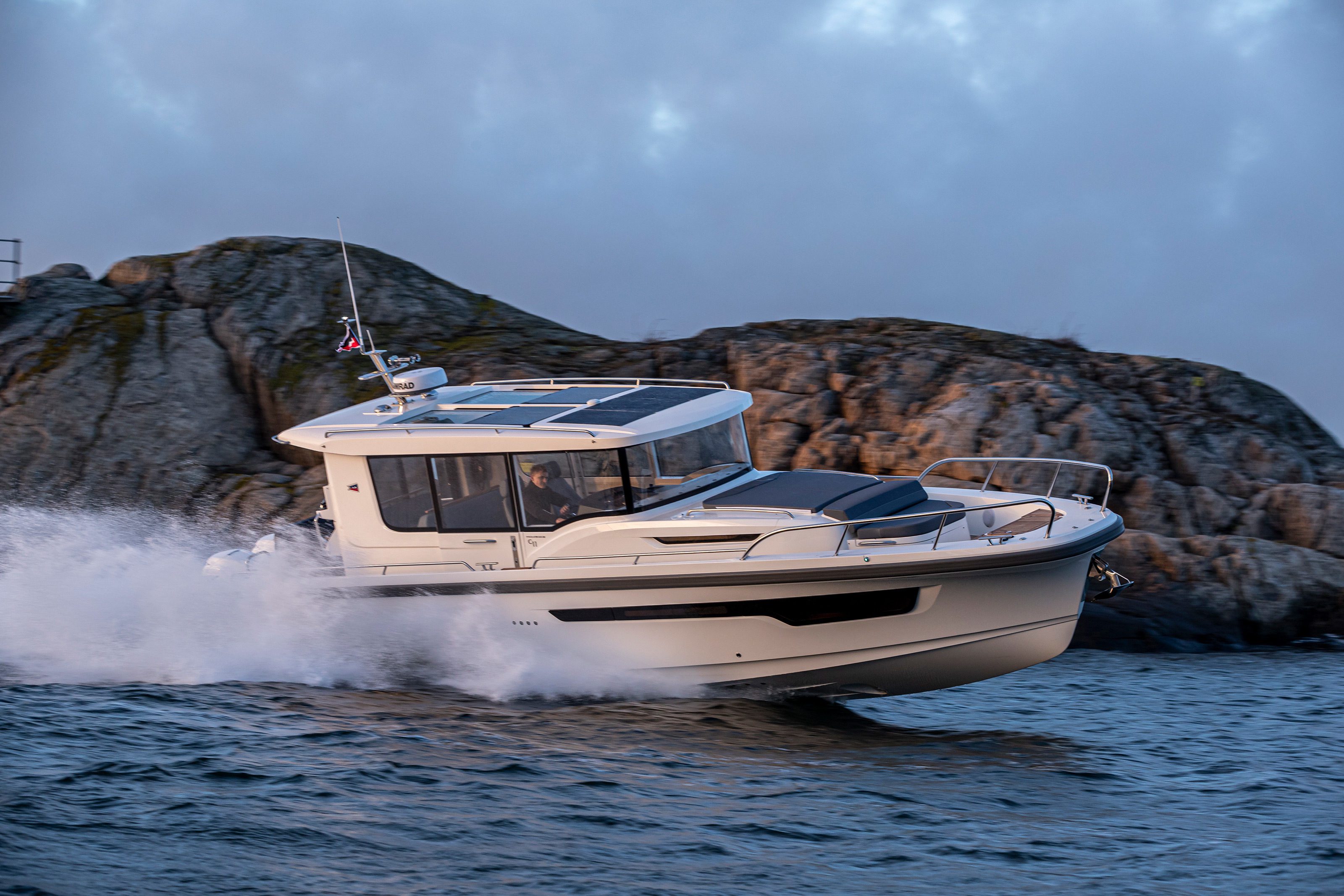 Boat driving fast on the ocean with a cliff in the background. The Nimbus C11