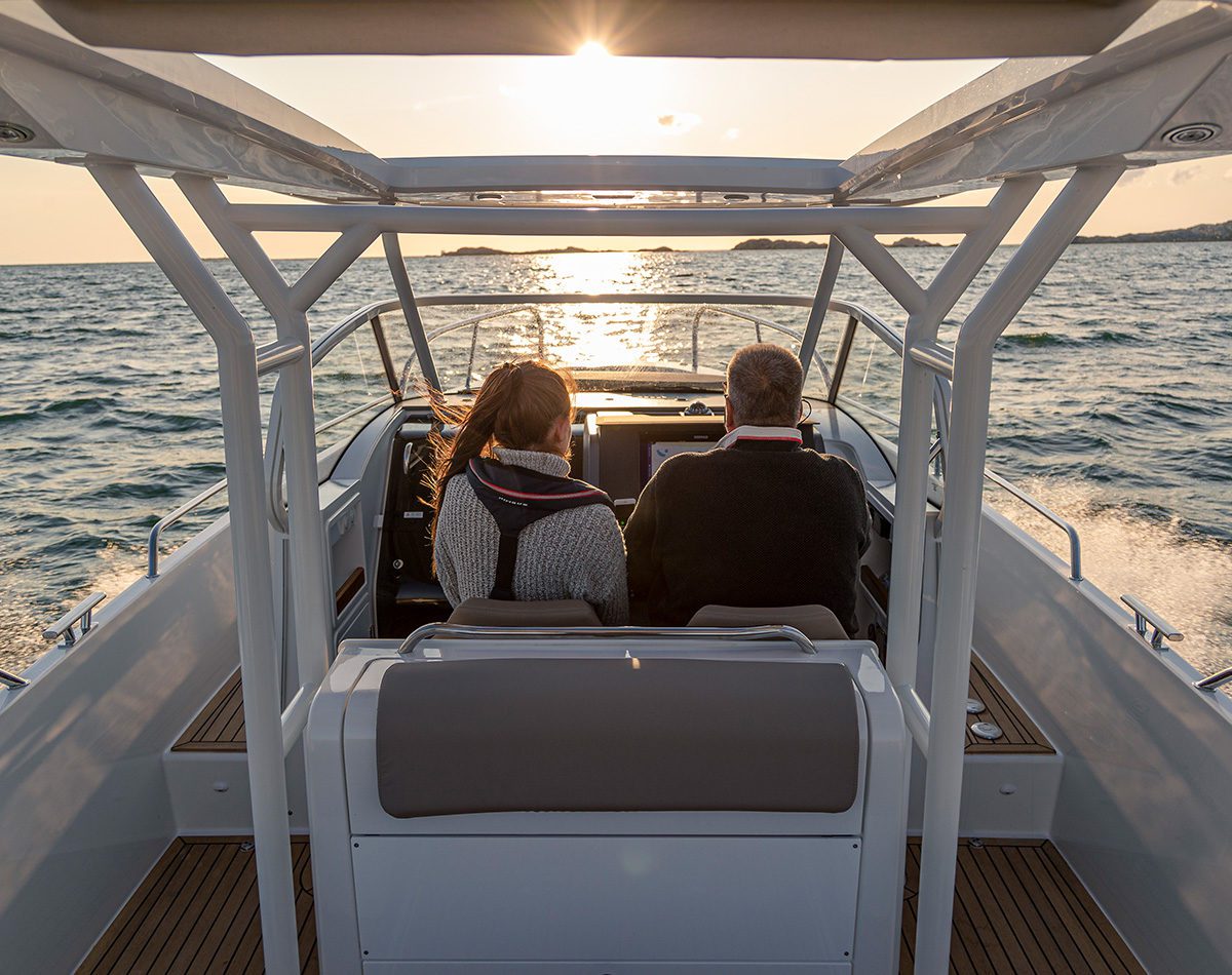 The inside of a Nimbus t9 motorboat driven by a man and a women in the sunset