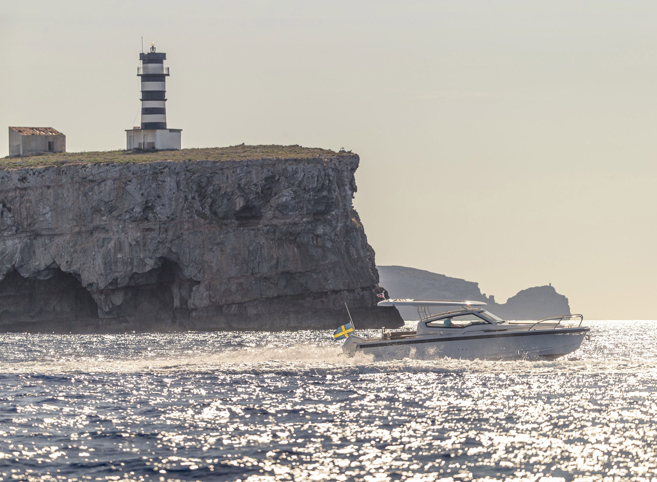 Nimbus boat next to a large rock with a tower on top