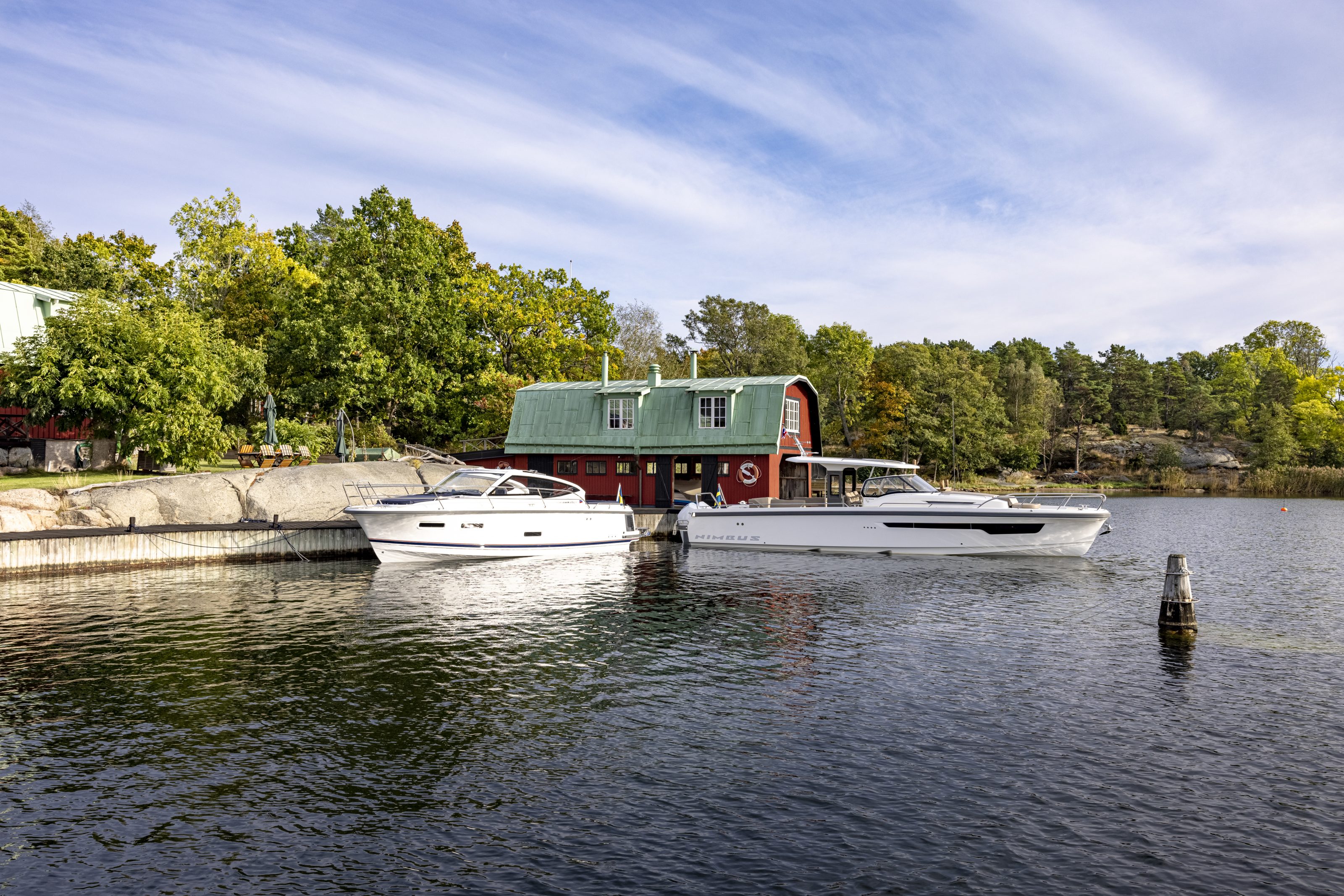 Nimbus boats in the ocean by the cliffs with trees and a house