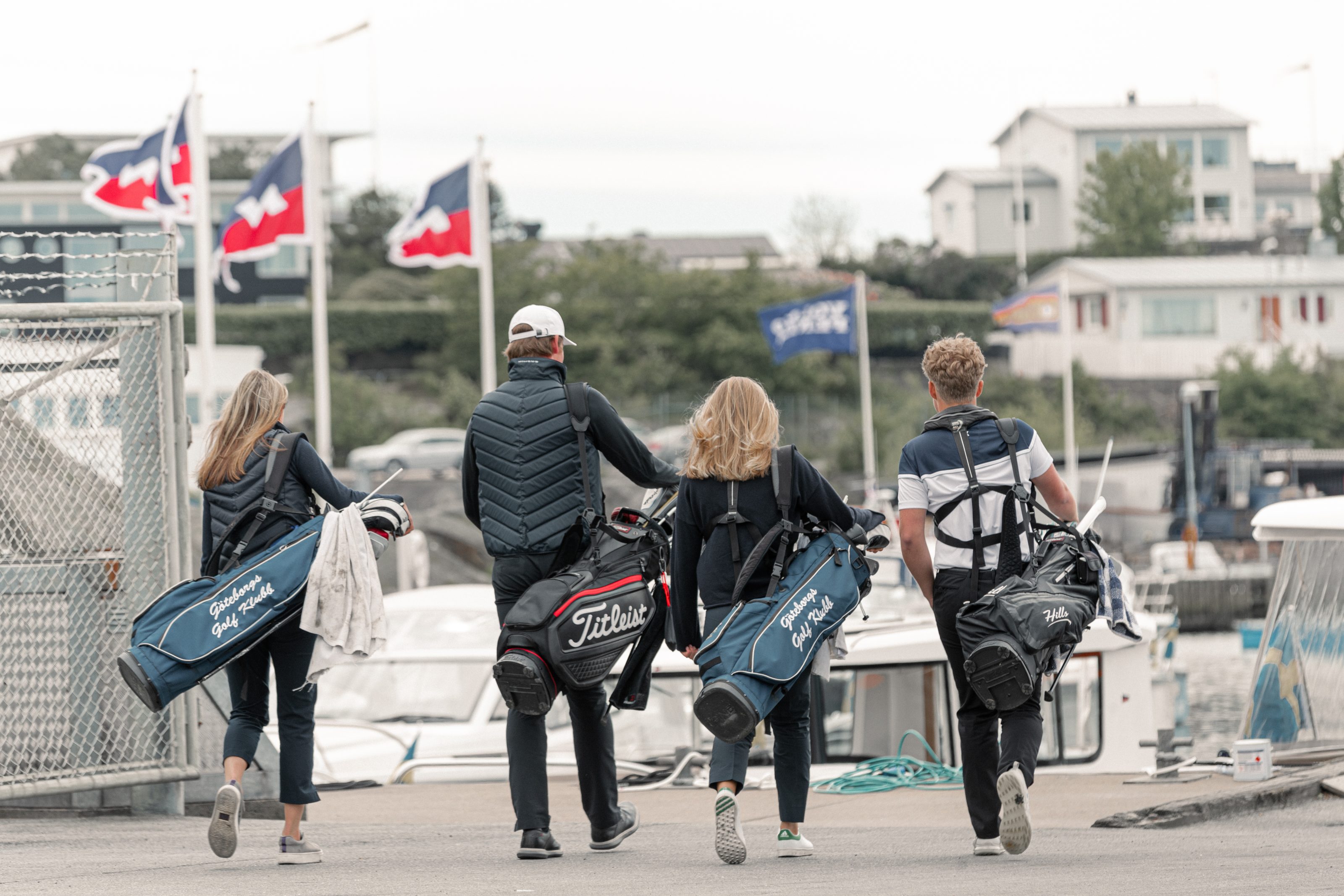 Family walking by the ocean in the harbour with golf clubs